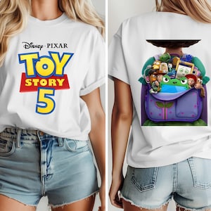 K&ouml;nnte beinhalten: Ein wei&szlig;es T-Shirt mit dem Disney Pixar Toy Story 5 Logo auf der Vorderseite. Die R&uuml;ckseite des Shirts zeigt eine Grafik eines violetten Rucksacks, der mit verschiedenen animierten Spielzeugfiguren gef&uuml;llt ist, darunter eine gr&uuml;ne Froschfigur.