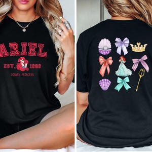 Może przedstawiać: Czarna koszulka z nadrukiem z przodu z napisem "ARIEL" w czerwonym kolorze, tekstem "EST. 1988" i grafiką Ariel. Tył koszulki przedstawia Ariel i inne grafiki tematyczne.