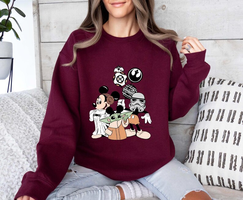 Puede incluir: Una sudadera granate con un dise&ntilde;o de Mickey Mouse, Baby Yoda y personajes de Star Wars. El dise&ntilde;o incluye a BB-8, un Stormtrooper y la Estrella de la Muerte. La sudadera es de manga larga.