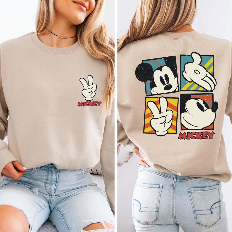 May include: Beige sweatshirt featuring a peace sign with the word "Mickey" below it. The back of the sweatshirt has four squares with Mickey Mouse images and the word "Mickey".