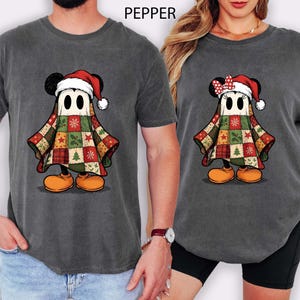 Peut inclure: T-shirts gris avec un personnage de dessin animé déguisé en fantôme de Noël. Le personnage porte un bonnet de Père Noël et une tenue en patchwork. Le personnage a des chaussures orange et des oreilles noires. Le mot "PEPPER" est imprimé en haut de l'image.