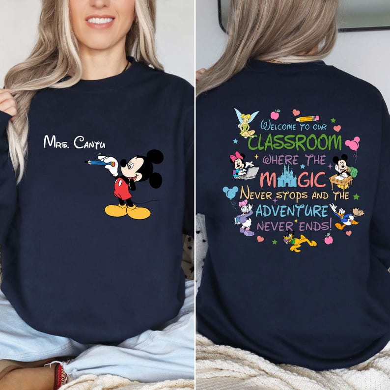 K&ouml;nnte beinhalten: Marineblaues Sweatshirt mit Mickey Mouse, der einen Bleistift h&auml;lt, und dem Namen "Mrs. Cantu". Auf der R&uuml;ckseite steht "Welcome to our Classroom where the Magic Never Stops and the Adventure Never Ends!" mit Disney-Figuren.