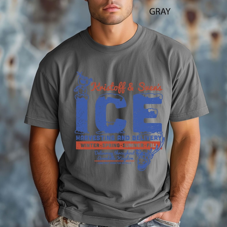 May include: Gray t-shirt with a vintage-style graphic. The design features the text "Kristoff & Sven's ICE" in blue and orange, with additional text below indicating "Harvesting and Delivery" and seasonal details. The shirt is a solid gray color.