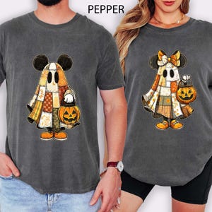 May include: Two grey t-shirts with a Halloween design. The design shows a cartoon ghost with Mickey Mouse ears, a patchwork outfit, and a jack-o'-lantern. The word "PEPPER" is printed at the top of the image.