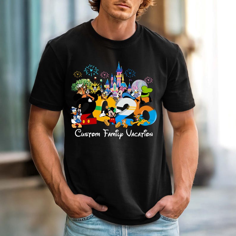 May include: Black t-shirt featuring a colorful graphic with the text "2020 Custom Family Vacation." The design includes cartoon characters, a castle, fireworks, and the number 2020 in vibrant colors. The shirt is short-sleeved.