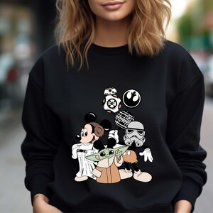 Puede incluir: Sudadera negra con un dise&ntilde;o de Mickey Mouse como la Princesa Leia, Baby Yoda, un Stormtrooper e iconos de Star Wars. El dise&ntilde;o incluye a BB-8 y el s&iacute;mbolo de la Alianza Rebelde. Cuello redondo.