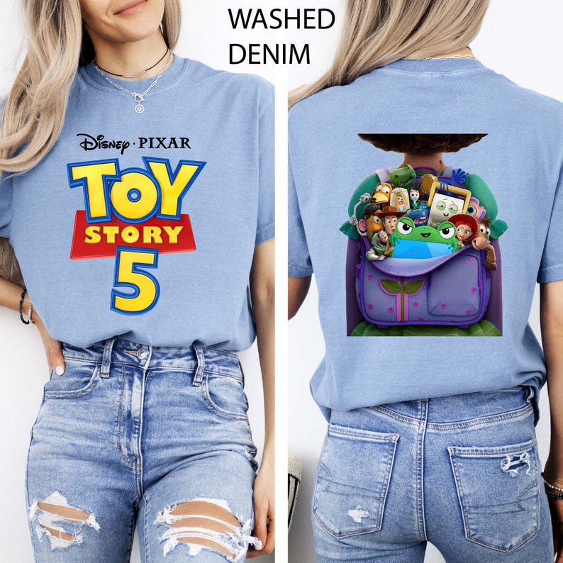 K&ouml;nnte beinhalten: Ein verwaschenes, denimblaues T-Shirt mit dem Disney Pixar Toy Story 5 Logo auf der Vorderseite in Gelb, Rot und Blau. Die R&uuml;ckseite des Shirts zeigt eine Grafik eines violetten Rucksacks, gef&uuml;llt mit verschiedenen animierten Spielzeugfiguren und einem gr&uuml;nen Frosch.