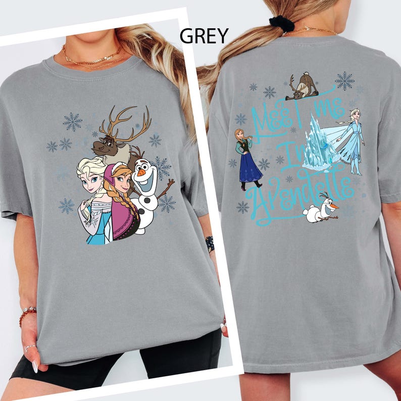 May include: Grey t-shirt featuring characters from the movie Frozen, including Elsa, Anna, Olaf, and Sven, with snowflake accents. The back of the shirt has the text "Meet Me In Arendelle" with additional characters and snowflakes.