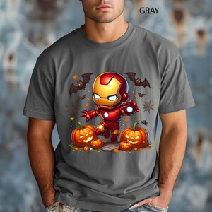 May include: Gray t-shirt featuring a cartoon Iron Man character in a Halloween theme. The design includes jack-o'-lanterns, bats, and spiderwebs. The word "GRAY" is printed at the top of the shirt.