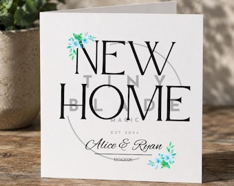 Può includere: Un biglietto di auguri bianco con le parole "NEW HOME" in grandi lettere nere. La carta include il testo "TINY BLONDE MAGIC" e "EST 2024". I nomi "Alice & Ryan" e la data "12042020" sono stampati sulla carta. Sono presenti accenti floreali blu e verdi.