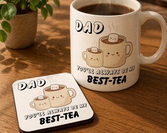 Può includere: Una tazza in ceramica bianca e un sottobicchiere abbinato con la scritta "DAD" e "YOU'LL ALWAYS BE MY BEST-TEA". La tazza è piena di un liquido scuro e il sottobicchiere è quadrato. Entrambi gli articoli presentano una simpatica illustrazione di due tazze di cioccolata calda.
