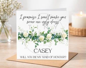Può includere: Biglietto bianco con design floreale e testo: "Prometto che non ti farò indossare un vestito brutto". Il biglietto dice anche "CASEY, VUOI ESSERE LA MIA DAMIGELLA D'ONORE?" Il biglietto è su una busta marrone.