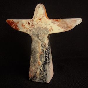 May include: A white, brown and black abstract sculpture of an angel with outstretched wings. The sculpture is made of a marbled material.