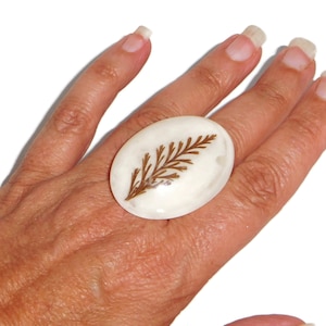 May include: White oval ring with a brown pressed leaf design.