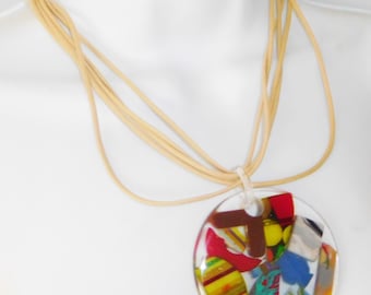 May include: A round, multi-colored pendant necklace with a beige cord. The pendant is made of clear resin with embedded colorful pieces of paper and plastic.