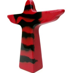 May include: A red and black abstract sculpture with a cross-like shape. The sculpture has a solid red base and a body with horizontal black stripes. The arms extend outward, creating a unique and modern design.