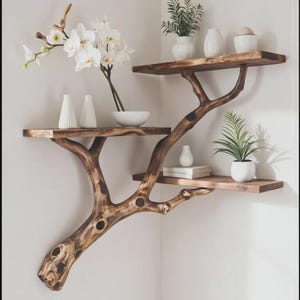 Op de afbeelding: Een houten hoekplank met een takontwerp. De planken bevatten witte vazen, een kom, boeken en potplanten. Witte orchideeën voegen een vleugje elegantie toe. De natuurlijke houtnerf en organische vorm creëren een rustieke, moderne esthetiek.