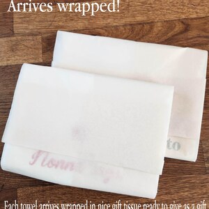 May include: Two white tissue paper wrapped towels. The text "Arrives wrapped!" is at the top of the image. The text "to" is visible on one towel and the text "I love" is visible on the other towel. The text "Each towel arrives wrapped in nice gift tissue ready to give as a gift." is at the bottom of the image.