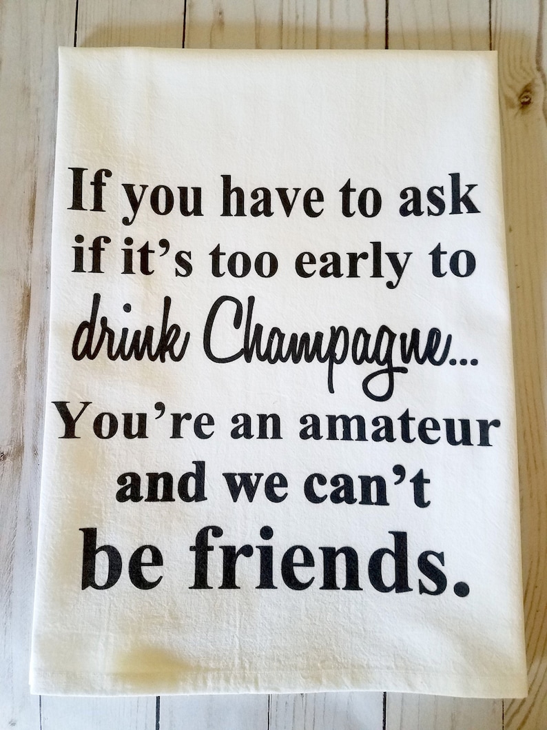 Funny Champagne theme tea towel. White towel printed with black ink. Size: 27in x 27in. Reads, "If you have to ask if it's too early to drink Champagne You're an amateur and we can't be friends."