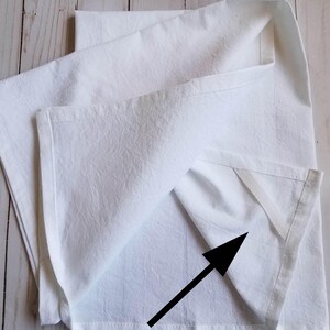 May include: A white kitchen towel with a white fabric hanger sewn into the top back corner.