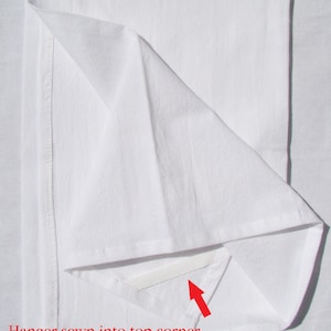May include: A white fabric sheet with a white hanger loop sewn into the top corner. The loop is visible through a small opening in the fabric.
