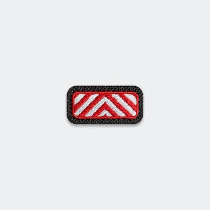 May include: A rectangular embroidered patch with rounded corners featuring a black border. The center design consists of alternating diagonal stripes in bright red and white, creating a chevron-like pattern within the black fabric background.