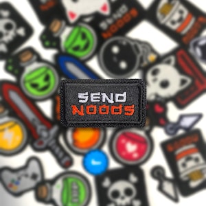 May include: Black rectangular patch with the words "SEND NOODS" embroidered in white and orange. The patch is surrounded by other patches with various designs, including a sword, a skull, and a cat.