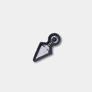 May include: Embroidered patch featuring a white kunai knife design with a black border. The patch has a circular handle and a triangular blade. This patch is suitable for jackets, bags, or other fabric items.