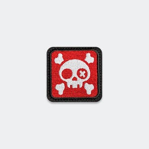 May include: A square embroidered patch featuring a white skull and crossbones design on a red background. The skull has one solid white eye socket and one eye socket with a white cross stitch detail. The patch has a thick black border.