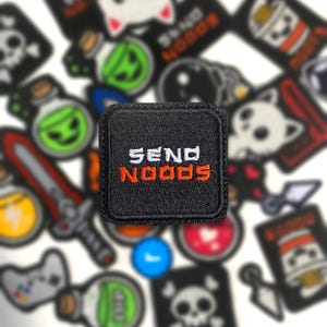 May include: Black square patch with the words "SEND NOODS" embroidered in white and orange thread. The patch is surrounded by other patches with various designs, including a skull, a potion bottle, and a sword.