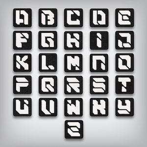 May include: A collection of black square patches, each displaying a white letter of the alphabet in a bold, geometric font. The letters A through Z are represented, with a stylized design. The patches are arranged in a grid pattern against a gray background.