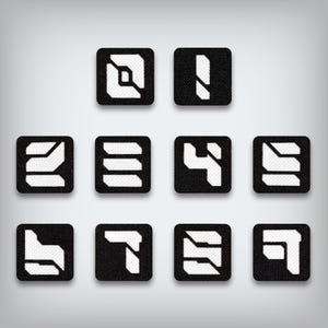 May include: Set of ten black and white number patches. Each patch features a different number from 0 to 9 in a futuristic, geometric font. The numbers are white and the background is black.
