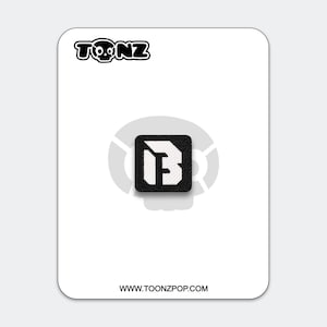 May include: A black and white patch featuring the letter "B" inside a square. The patch is on a white card with the text "TOONZ" above and "WWW.TOONZPOP.COM" below. The "TOONZ" logo includes a skull.