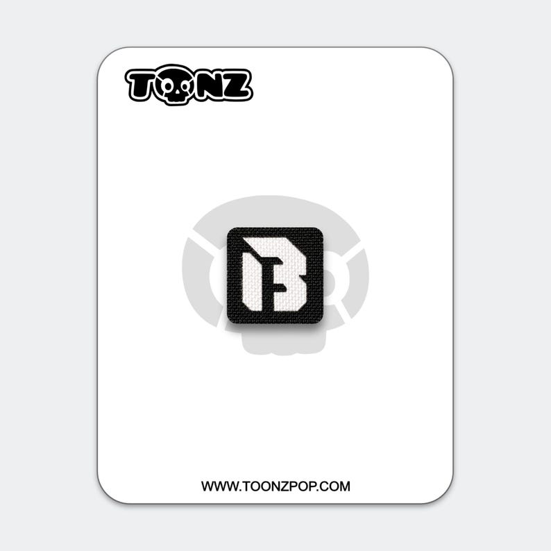 May include: A black and white patch featuring the letter "B" inside a square. The patch is on a white card with the text "TOONZ" above and "WWW.TOONZPOP.COM" below. The "TOONZ" logo includes a skull.