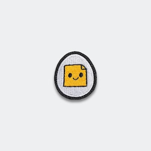May include: Embroidered patch featuring a smiling yellow sticky note with a folded corner. The patch is set against a white background, framed by a black border, and shaped like an egg. A fun, whimsical design.