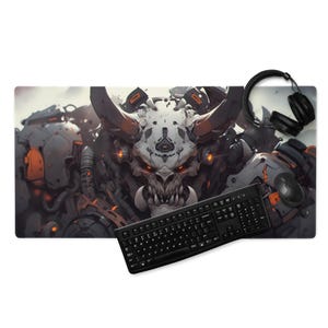 May include: A large rectangular mouse pad featuring a detailed illustration of a demonic creature with horns and glowing orange accents. A black keyboard, mouse, and headphones are placed on the pad.