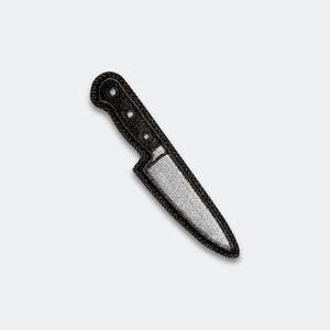 May include: Embroidered patch of a kitchen knife with a silver blade and a black handle. The patch has a black border and is designed to be ironed or sewn onto fabric. The knife is a common kitchen tool.