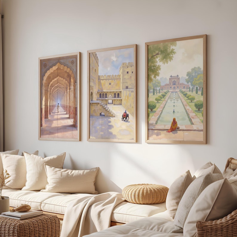 May include: Three framed art prints depicting Indian architecture and landscapes. The artwork features detailed paintings of archways, forts, and gardens with figures. The frames are light-colored wood, and the overall aesthetic is warm and inviting.