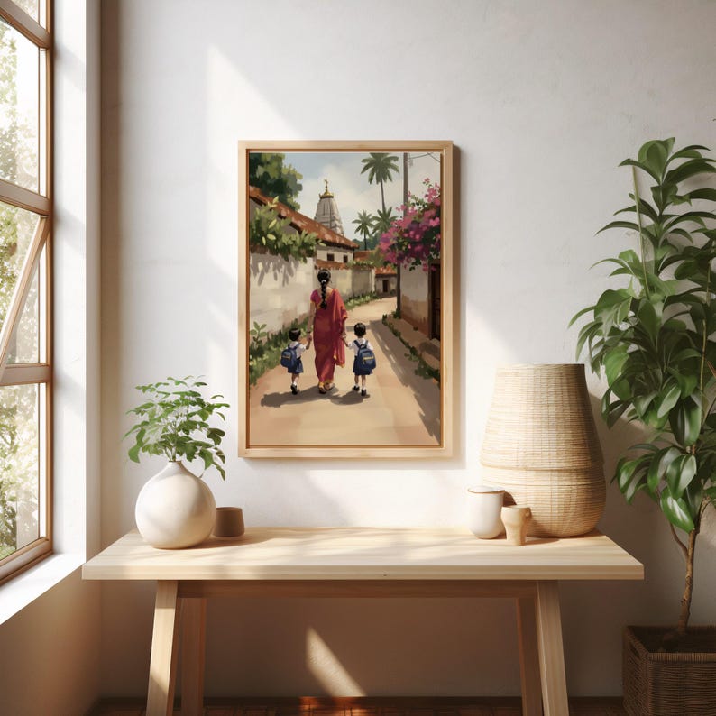 May include: Framed watercolor print depicting a woman in a red sari walking with two children down a village path. The artwork features a temple, palm trees, and flowering vines, all in soft, muted colors. The frame is a light wood.