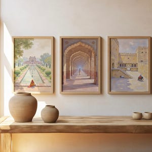 May include: Three framed watercolor prints depicting Indian architecture hang above a wooden table. The prints feature scenes of archways, courtyards, and gardens. Two beige ceramic vases and three small bowls sit on the table.