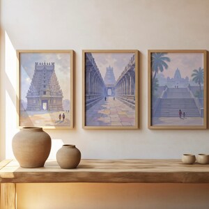 May include: Three framed prints depicting ancient temples in shades of blue, gray, and beige. The prints are displayed above a wooden table with two ceramic vases and three small bowls. The room has a window with natural light.