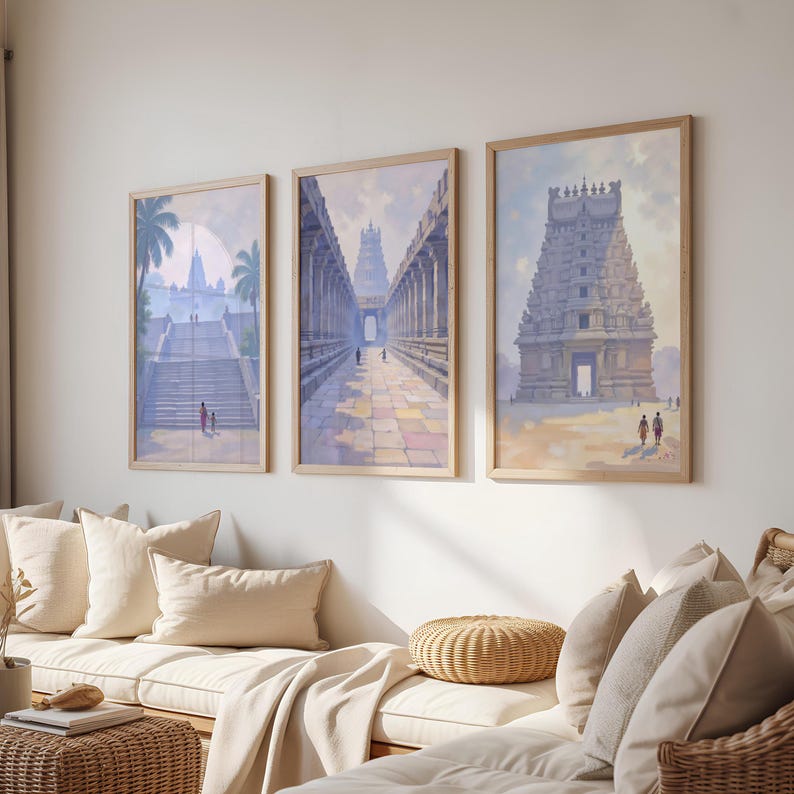 May include: Three framed art prints depicting ancient temples. The artwork features detailed architectural renderings in soft pastel colors, with figures and palm trees. The frames are a light wood color, and the prints are displayed above a cream-colored sofa.