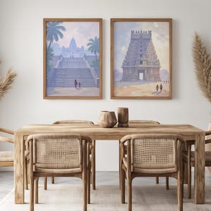May include: Two framed watercolor prints of Indian temples hang above a wooden dining table with six woven chairs. The artwork features temples with palm trees and figures. Decorative vases and pampas grass complete the scene.