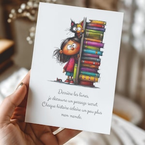 Peut inclure: Une carte de vœux rectangulaire blanche illustrée d'un dessin animé représentant un enfant aux cheveux bruns et un chat cachés derrière une haute pile de livres colorés. Sous l'illustration, le texte indique : Derrière les livres, je découvre un passage secret. Chaque histoire éclaire un peu plus mon monde.