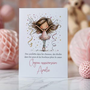 Op de afbeelding: Een verjaardagskaart met een aquarel illustratie van een meisje in een roze jurk, omringd door confetti en slingers. De kaart heeft Franse tekst, waaronder een roze "Gelukkige verjaardag" boodschap en een naam. Roze en gouden decoraties op de achtergrond.