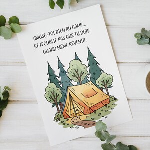 Peut inclure: Illustration sur une carte blanche avec le texte "AMUSE-TOI BIEN AU CAMP... ET N'OUBLIE PAS QUE TU DOIS QUAND MÊME REVENIR." L'image représente une tente, des arbres et un chemin. Une tasse de café est à côté.