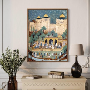 May include: A framed artwork showing a detailed illustration of a Middle Eastern city scene. The artwork features a light-coloured fortress with gold-domed towers, surrounded by trees and figures. The colour palette includes blues, greens, and golds, with a wooden frame.