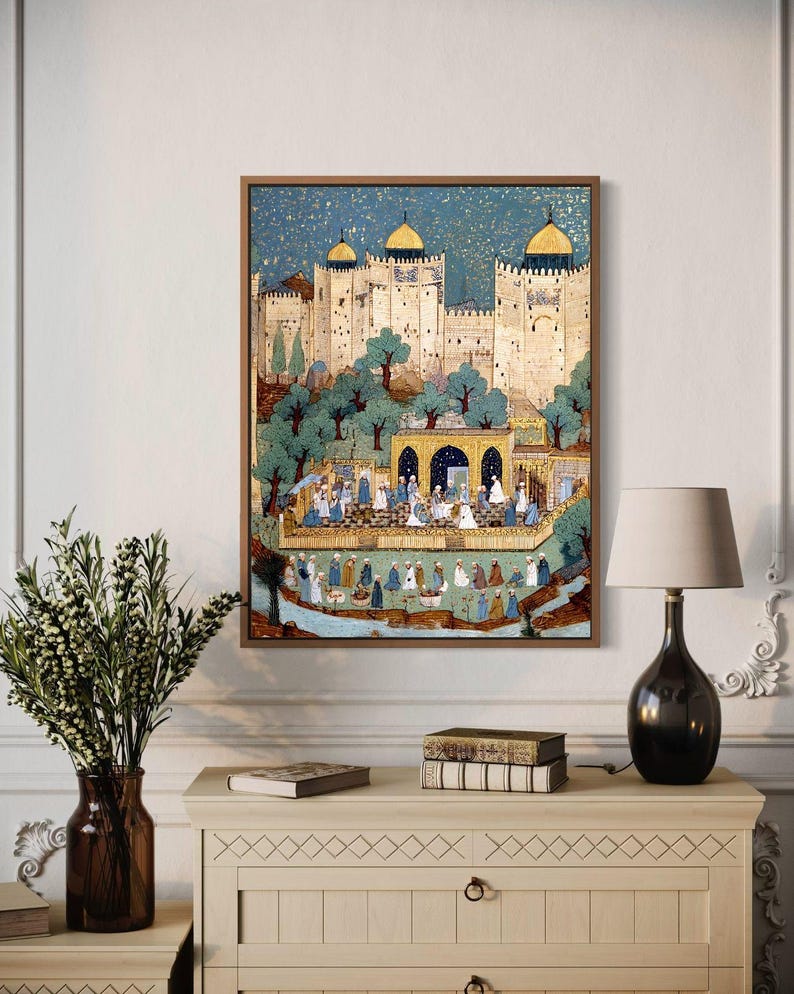 May include: A framed artwork showing a detailed illustration of a Middle Eastern city scene. The artwork features a light-coloured fortress with gold-domed towers, surrounded by trees and figures. The colour palette includes blues, greens, and golds, with a wooden frame.