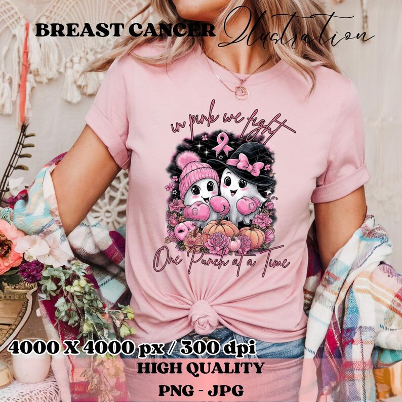 May include: Pink t-shirt with a graphic featuring two cartoon ghosts wearing pink hats and boxing gloves, surrounded by pink flowers and pumpkins. The text "in pink we fight" and "One Punch at a Time" are also visible.