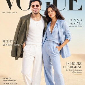 Puede incluir: Una portada de revista titulada VOGUE THE TRAVEL ISSUE con dos personas. Una viste un blazer verde oliva sobre una camiseta blanca y pantalones blancos. La otra viste una camisa azul claro con blazer y pantalones a juego.